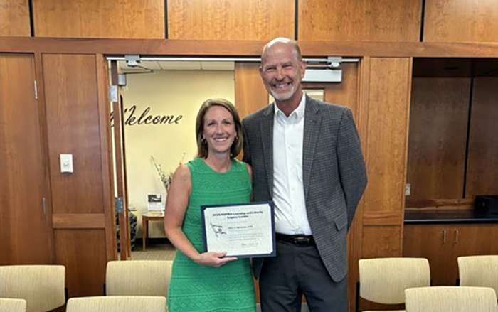 Holly McCaw, APR, Director of Otsego Public Schools holds her award after being honored by her Board of Education.